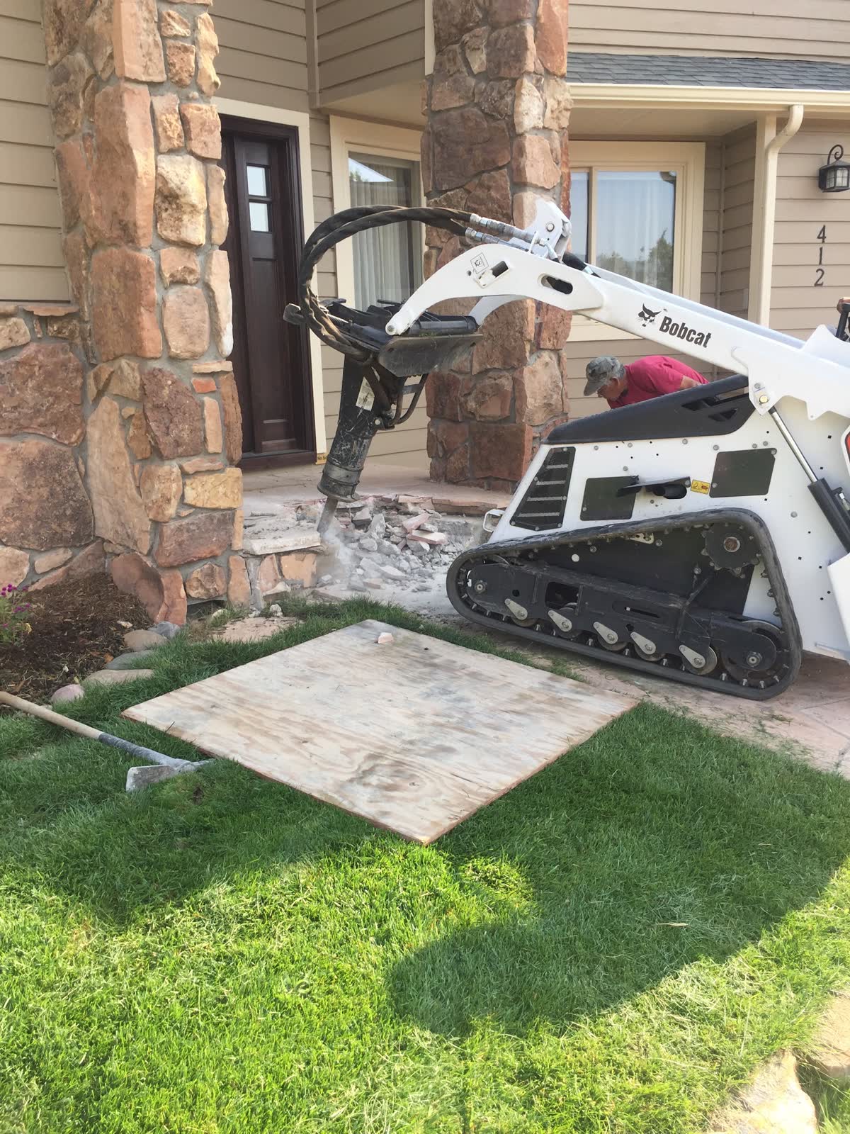 A compact track loader breaking out an old concrete slab