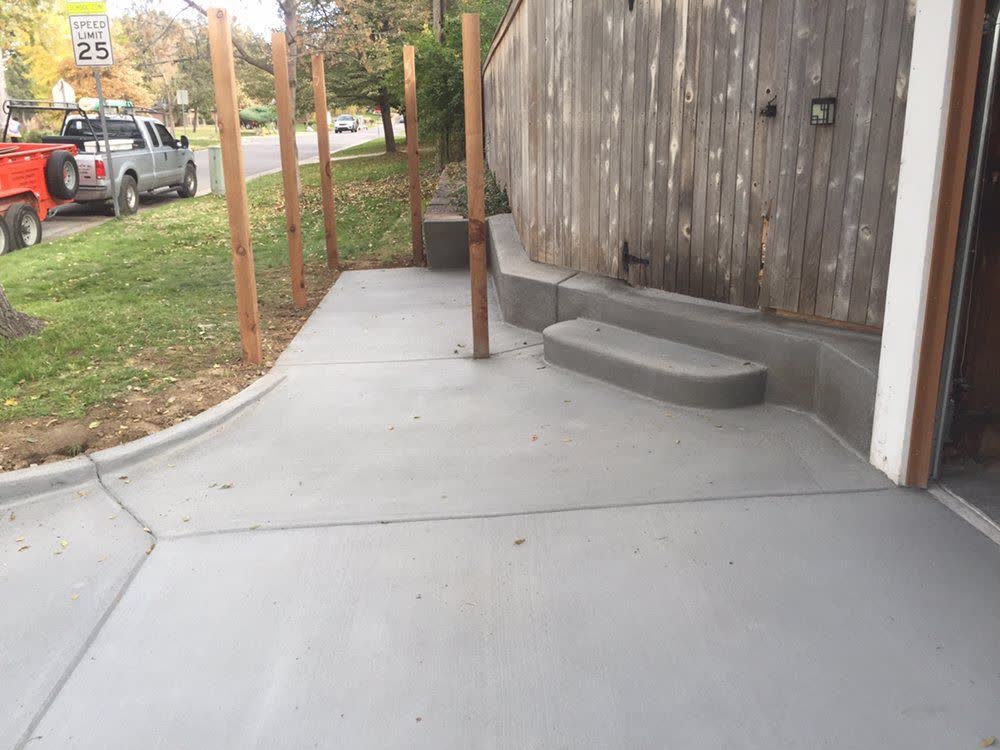 A drive apron, walkway and low step poured together beside a fence