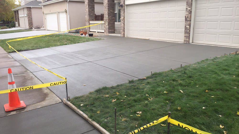 A wide new driveway taped off to cure in front of a three-car garage