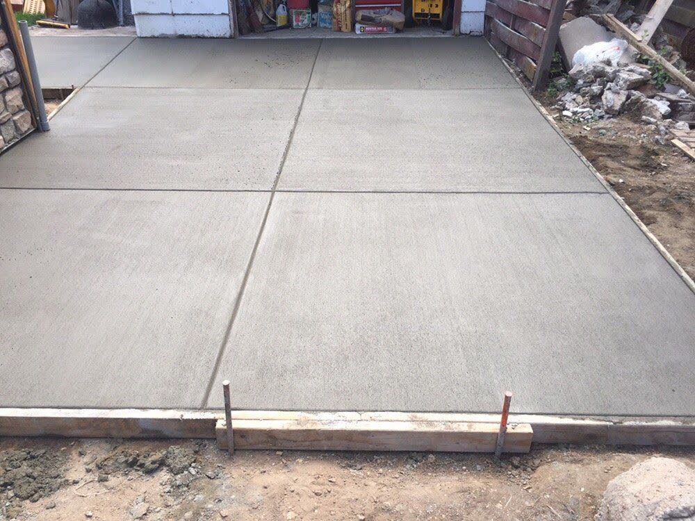 A fresh slab between two garages with a clean saw-cut joint down the middle